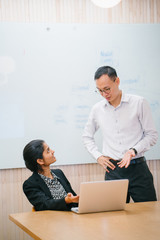 A portrait of two professional business people talking inside a conference room. They are deep in...