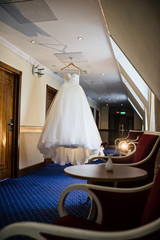 Fototapeta na wymiar White wedding dress of the bride hanging in the hotel lobby
