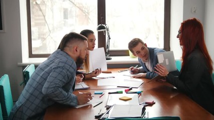 Business concept. A working team at the conference. Woman showing information on her laptop and her colleagues looking at the screen