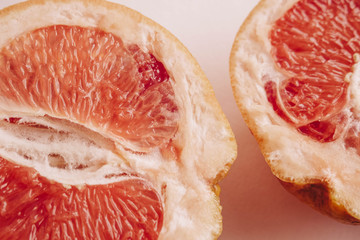 Halved grapefruit close up. Citrus fruit. Healthy eating. Pink color wallpaper. White background