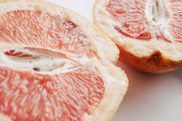 Halved grapefruit close up. Citrus fruit. Healthy eating. Pink color wallpaper. White background