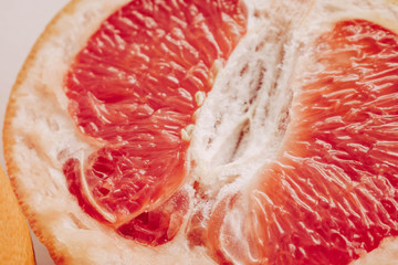 Halved grapefruit close up. Citrus fruit. Healthy eating. Pink color wallpaper. White background