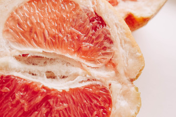 Halved grapefruit close up. Citrus fruit. Healthy eating. Pink color wallpaper. White background