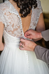 Obraz na płótnie Canvas Mom's hands tie the bride's dress