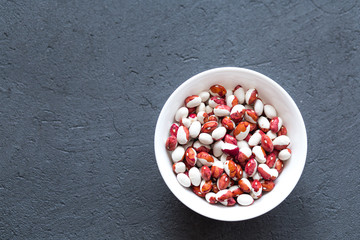 The coloreful haricot bean on the white plate on gray stone table