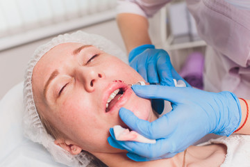 The doctor cosmetologist makes Lip augmentation procedure of a beautiful woman in a beauty...