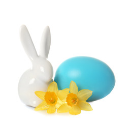 Cute ceramic Easter bunny with flower and dyed egg on white background