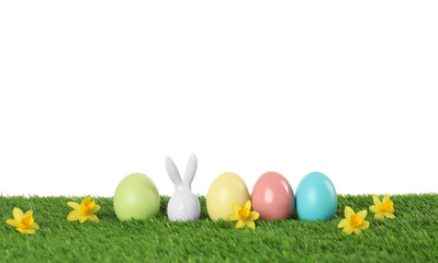 Dyed Easter eggs and bunny ears on green grass against white background