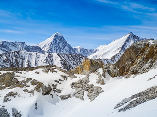 Snow-capped mountain peaks against a bright blue sky. The concept of recreation and adventure.