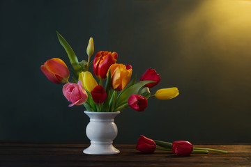 beautiful tulips in vase on green background