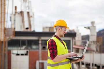 Industrial worker in reflective vest using laptop