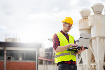Industrial worker in reflective vest using laptop