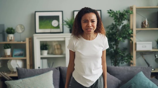 Portrait of angry African American woman yelling and gesturing expressing negative emotions standing in modern apartment. Human feelings and people concept.