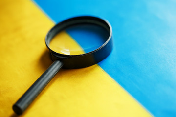 UKRAINE flag looking through a magnifying glass. Spying and monitoring Ukraine. Monitoring the state of the Ukrainian people