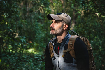 Obraz premium Man walking in a beautiful green forest with sunlight