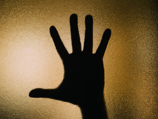 Silhouette of open hand on a glass.