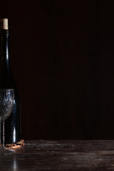 Wine bottle with wineglass in black background.