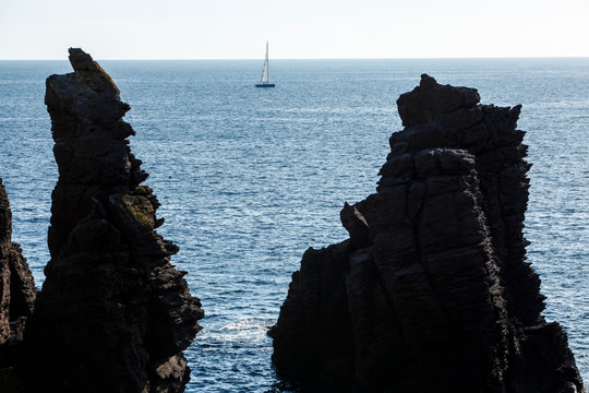 Barca a vela in lontananza  in mezzo agli scogli - Calasetta - Sardegna