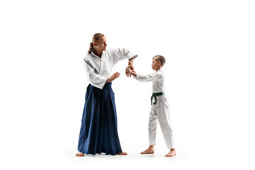 Fototapeta premium Man and teen boy fighting at Aikido training in martial arts school. Healthy lifestyle and sports concept. Fightrers in white kimono on white background. Karate men with concentrated faces in uniform.