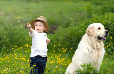Portrait of cute caucasian blondie baby boy with big dog labrador  in country side background. Nature, outdoors, childhood concept