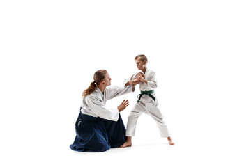 Man and teen boy fighting at Aikido training in martial arts school. Healthy lifestyle and sports concept. Fightrers in white kimono on white background. Karate men with concentrated faces in uniform.