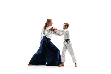 Man and teen boy fighting at Aikido training in martial arts school. Healthy lifestyle and sports concept. Fightrers in white kimono on white background. Karate men with concentrated faces in uniform.