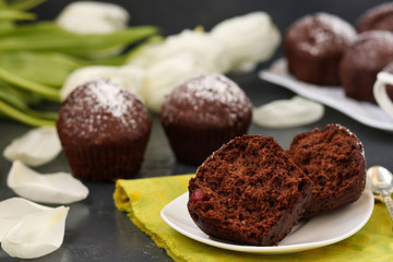 Chocolate muffins with cherry, covered with powder sugar located on a dark background