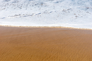 Beach sea sand with a soft wave of surf. Beach background