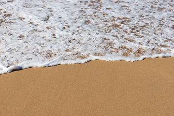 Beach sea sand with a soft wave of surf. Beach background