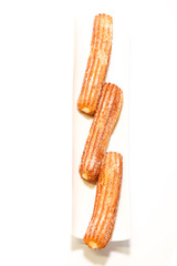 spanish fritters filled with cream on white background on white dish