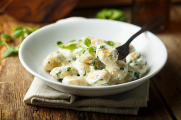 Homemade potato gnocchi with creamy basil sauce