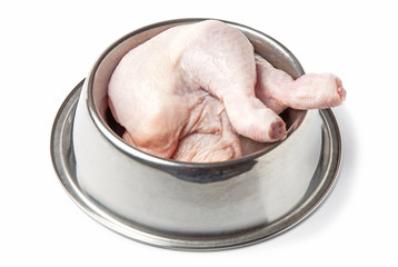 Pet food. Chicken parts, legs, in a metal bowl, isolated on a white background. 