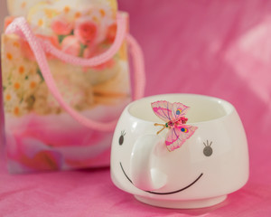 On a pink background with white Cup and pink butterfly