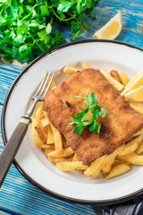 A piece of fried cod with fries on a plate.