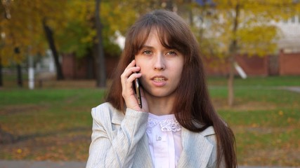 Businesswoman in business suit talking on smartphone and smiling. Girl communicates by phone. Close-up.