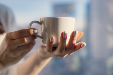 Close up of women's hands holding white mug with blank copy space scree for your advertising text message or promotional content, sweet coffee or tea.