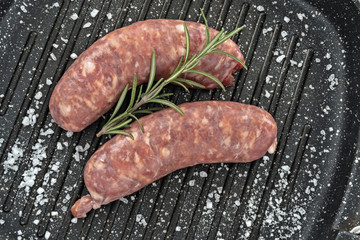 salsiccia cruda su griglia con rosmarino primo piano