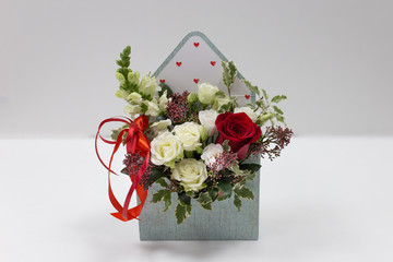 Cute floral arrangement (gift) of fresh flowers in a box in the form of an envelope on a light...