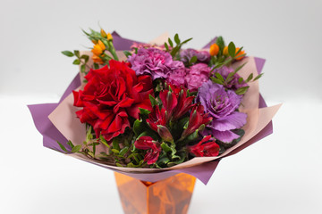 Bright bouquet (red, yellow, green, lilac) of roses, gerberas, alstroemeria and greenery on a light background