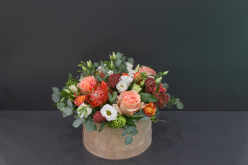 An impressive composition of roses and exotic flowers with leaves in a hat box on a gray background