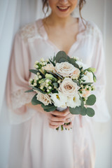 bride in a bathrobe holding her wedding bouquet