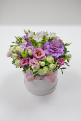 Wonderful flower arrangement (white, lilac, pink, light green color) in a white hat box on a light background