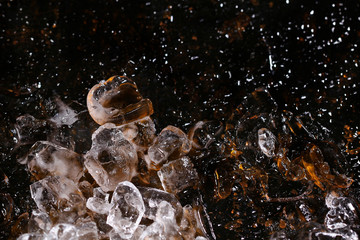 Ice on colored glass, black background and golden glitter. A concept of beautiful texture.
