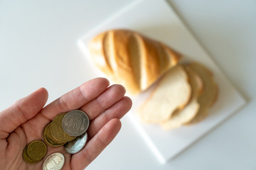 The coins in the girl’s hand over the table on which the sliced ​​bread lies, demonstrates the lack of money for food