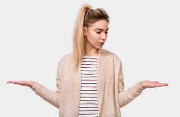 Portrait of puzzled blonde pretty young woman shrug shoulders, looks uncertain, confused and...