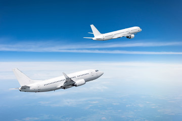 Two passenger aircraft gain altitude after take off.