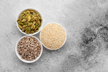 Assortment of nuts in white saucers on a concrete background. Food mix background, top view, copy space, banner