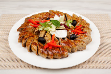 Baked sausage sliced with vegetables on a large platter.