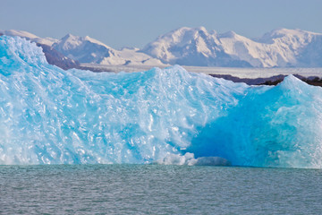 Large blue bright icebergs float on the waters of Lago Argentino lake, El Calafate, Argentina in sunshine day.