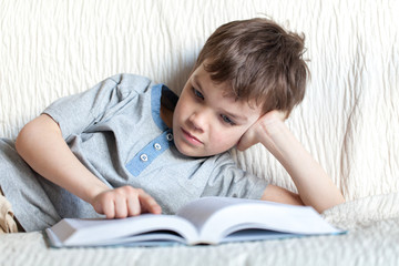 Boy reading a book on the couch in the room